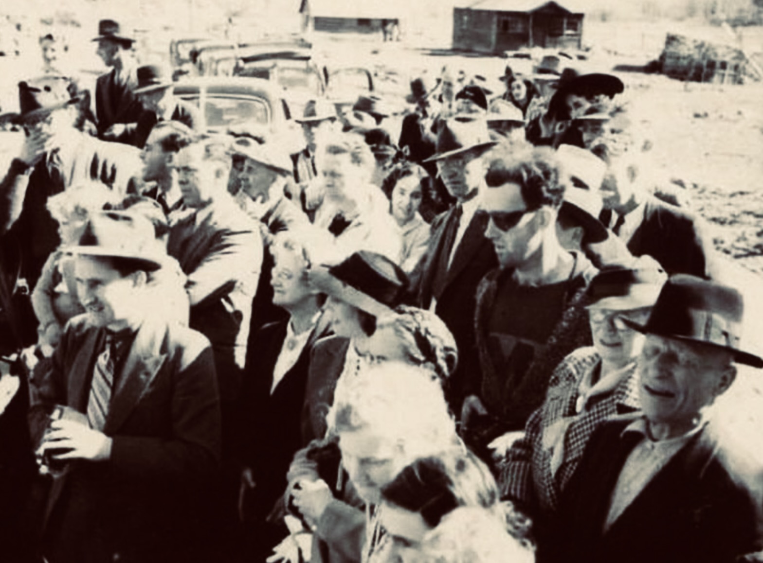 Fotografía en blanco y negro de una multitud de personas vestidas con ropa de la década de 1940. En el centro de la imagen destaca un hombre con gafas de sol oscuras, camiseta estampada y un suéter con cremallera, cuyo atuendo y apariencia moderna contrastan con la vestimenta del resto, generando teorías sobre un posible viajero en el tiempo.
