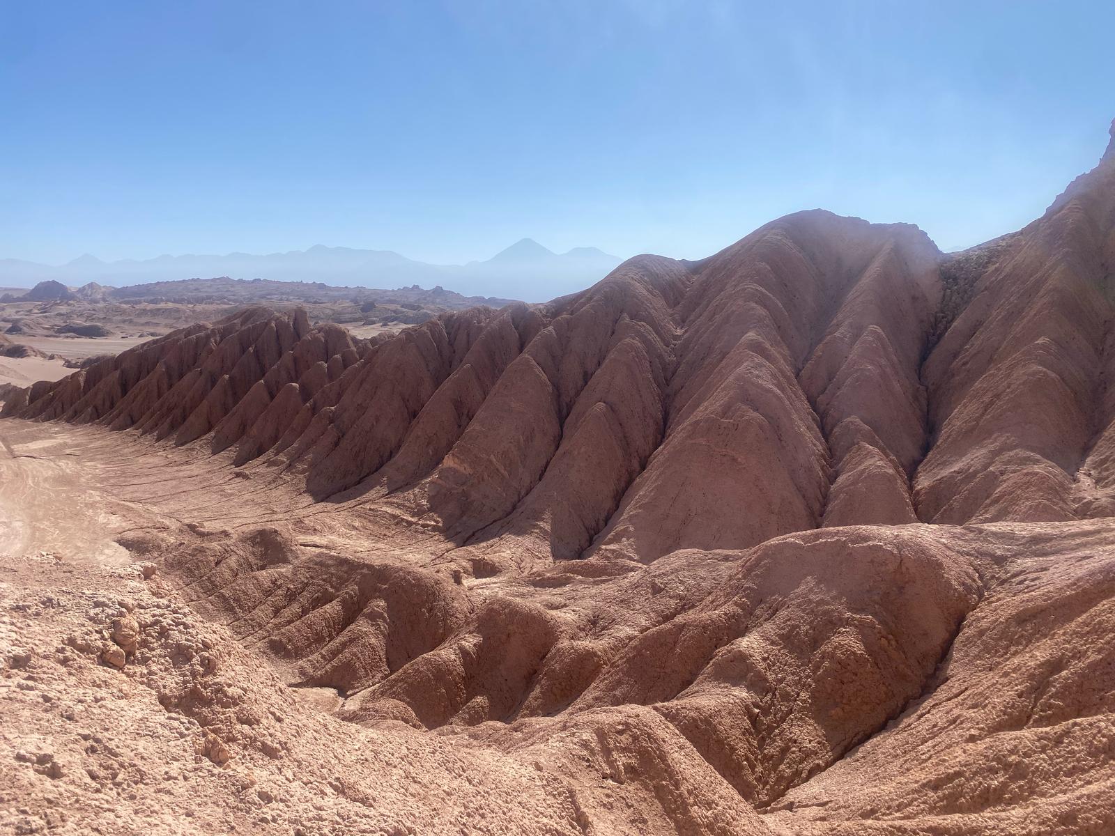 desierto-atacama Paisaje árido del desierto de Atacama, con formaciones rocosas esculpidas por la erosión y un cielo despejado. Esta región, una de las más secas del mundo, ha conservado momias de forma natural durante milenios, proporcionando una ventana única a las antiguas culturas prehispánicas y sus rituales funerarios.